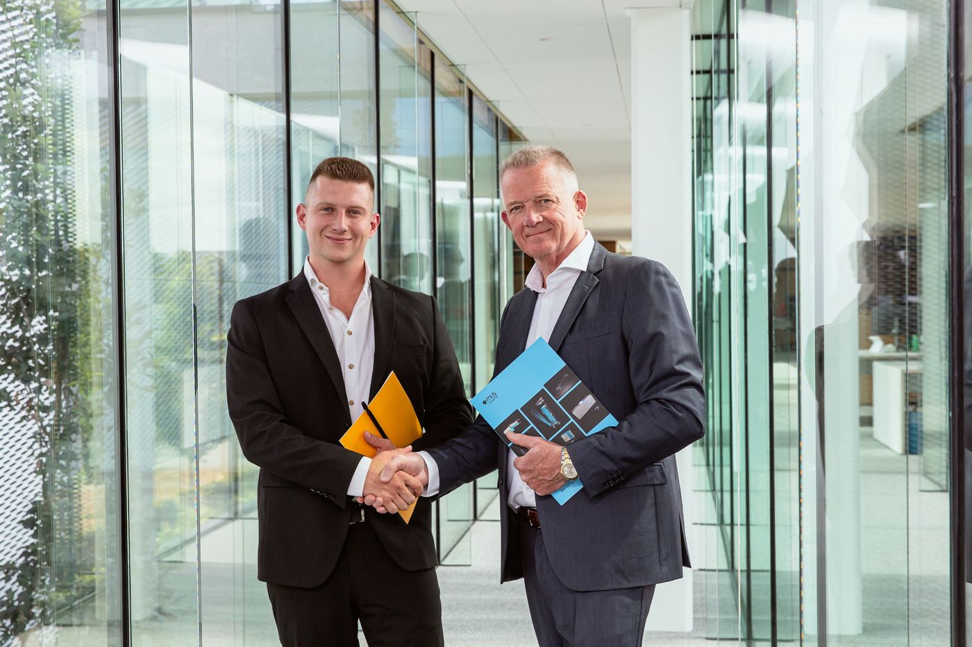Two generations of MLS shaking hands in the modern headquarters